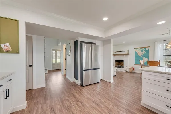 a kitchen with granite countertop wooden floors white cabinets and stainless steel appliances