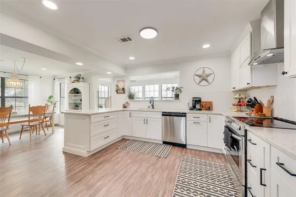 a kitchen with white cabinets and wooden floor