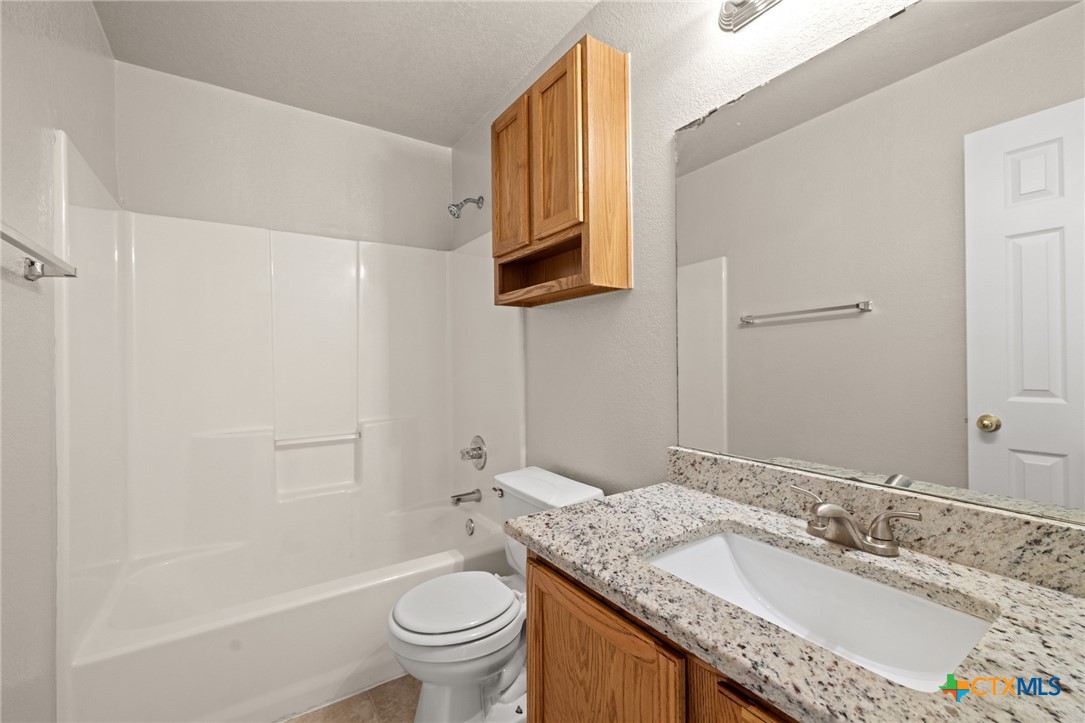 214 Timber Ridge Drive Nolanville, TX 76559 - Photo 20 of 31 a bathroom with a granite countertop sink toilet and a mirror