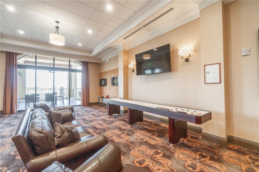 9596 Trevi Court, Unit 5414 Naples, FL 34113 - Photo 33 of 34 a living room with furniture a flat screen tv and a floor to ceiling window