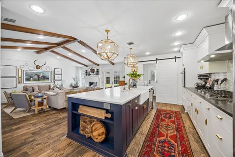 a large kitchen with stainless steel appliances granite countertop a lot of counter space and wooden floors