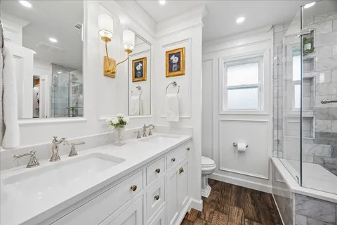 a bathroom with double vanity sink a mirror and a shower