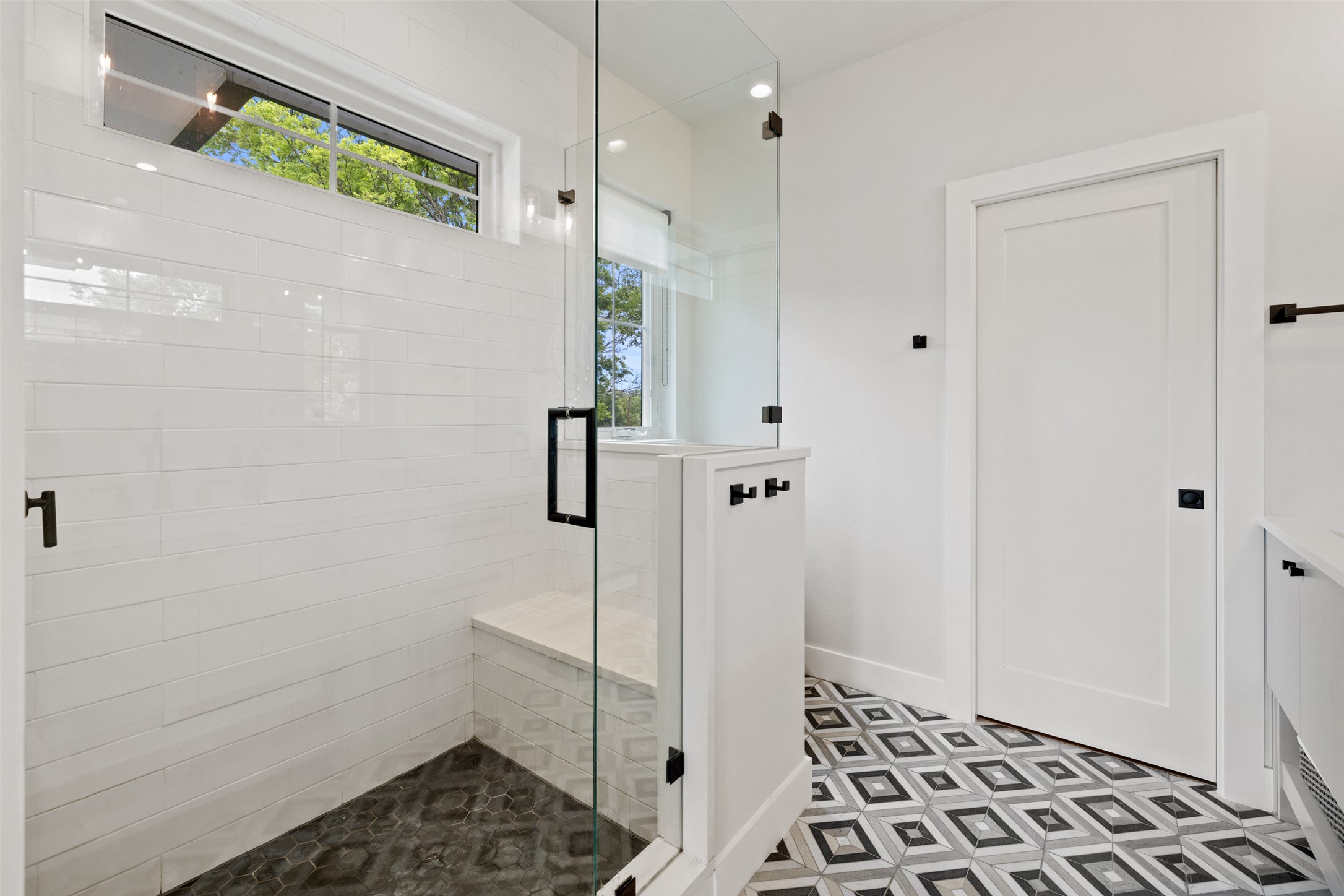 1504 Ruth Avenue, Unit 3 Austin, TX 78757 - Photo 24 of 39 A striking glass-enclosed shower with a built-in bench and a patterned tile floor.