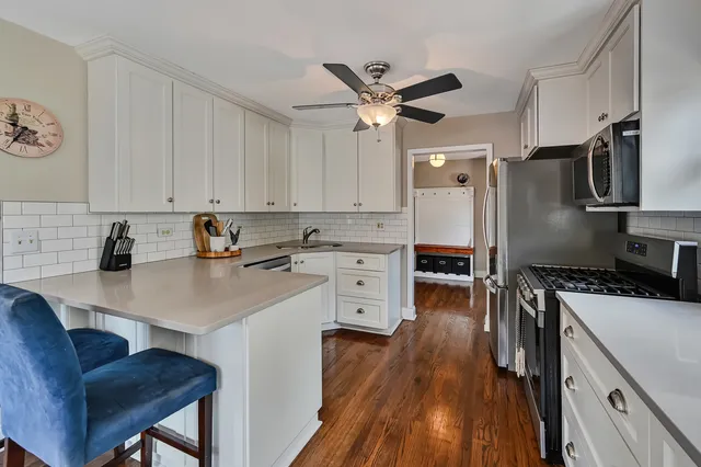 a kitchen with stainless steel appliances a stove a sink a refrigerator wooden floor and cabinets