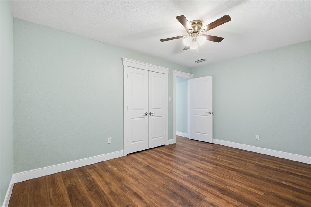 104 Murls Lake Road Weatherford, TX 76085 - Photo 25 of 39 Wood-finish flooring, light blue wall paint, white trim, white bi-fold closet doors, and a ceiling fan with integrated lighting