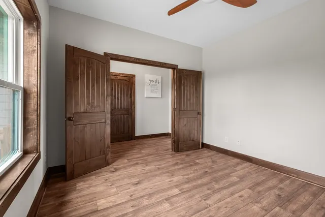 a view of an empty room with wooden floor and a window