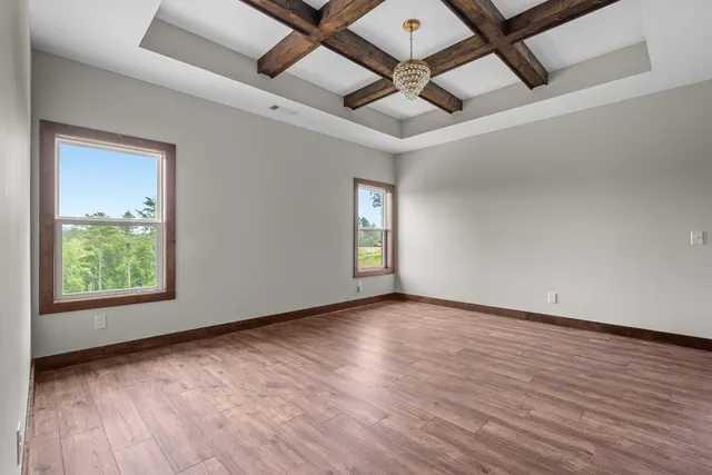 an empty room with wooden floor chandelier fan and windows