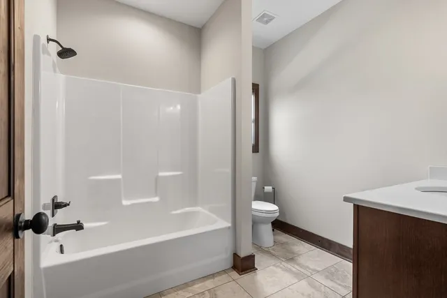 a bathroom with a granite countertop bathtub shower and toilet