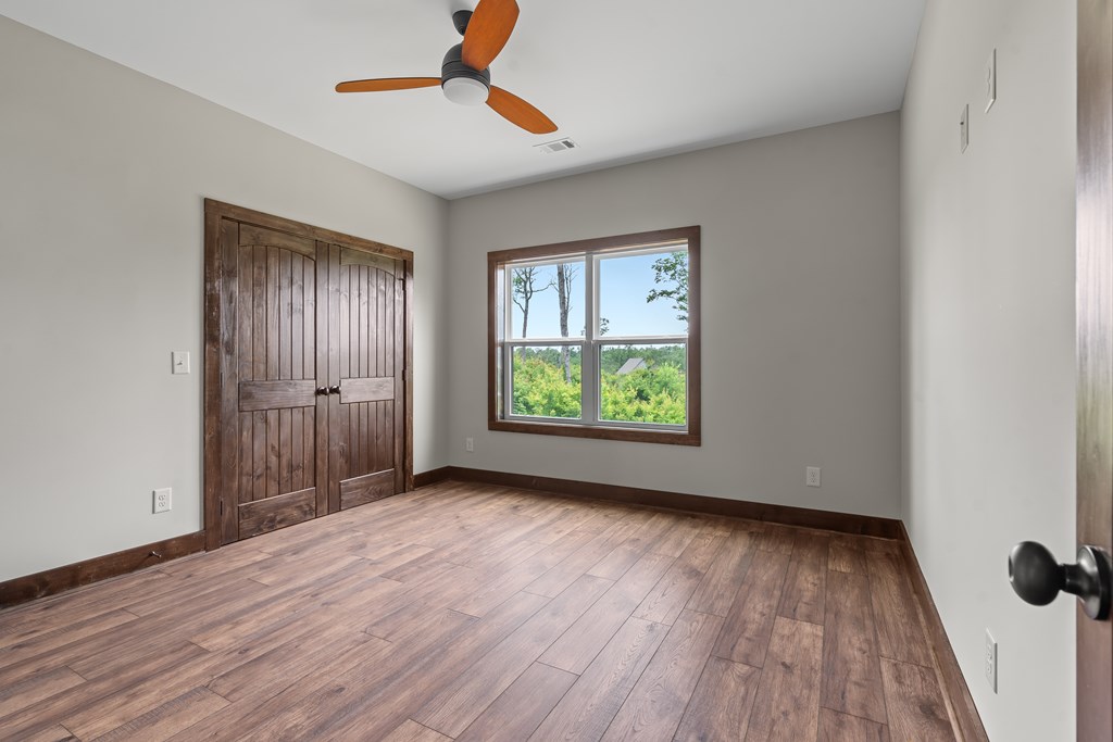 39 Mountaintown Overlook Ellijay, GA 30540 - Photo 33 of 51 an empty room with wooden floor chandelier fan and windows