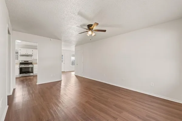 an empty room with wooden floor and a kitchen space with wooden floor