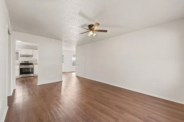 an empty room with wooden floor and a kitchen space with wooden floor