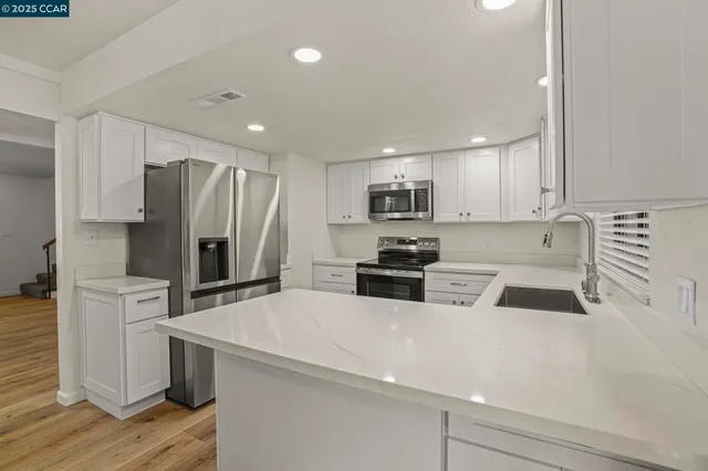 a kitchen with a refrigerator a stove a sink cabinets and wooden floor