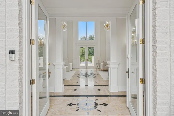 a view of a dining room with furniture a chandelier and large windows