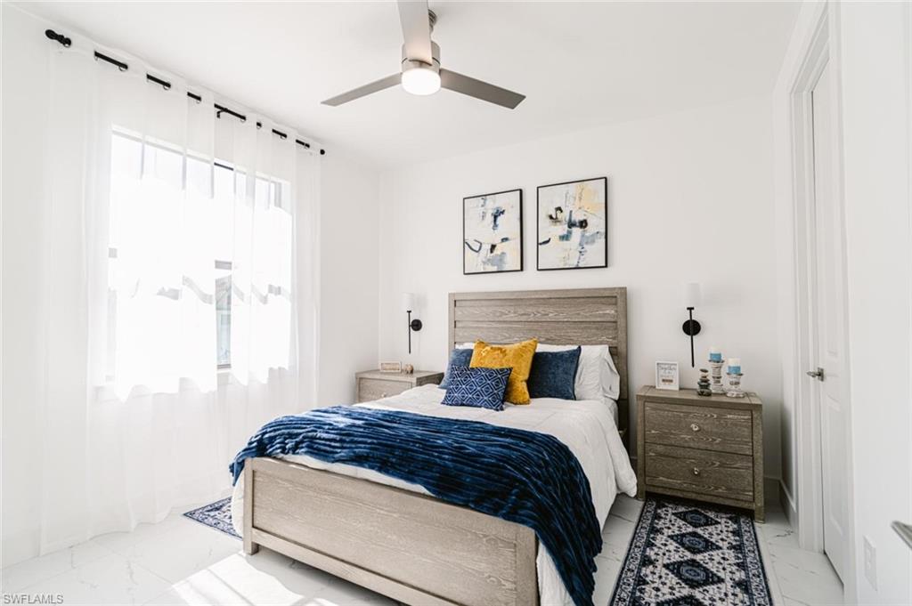 907 Homestead Road South Lehigh Acres, FL 33974 - Photo 18 of 43 Bright bedroom featuring a large window with sheer white curtains, a ceiling fan with integrated lighting, and white flooring