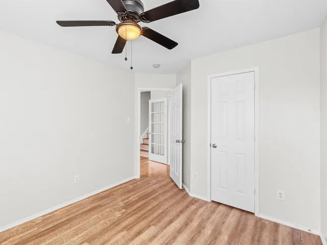 an empty room with wooden floor ceiling fan and window