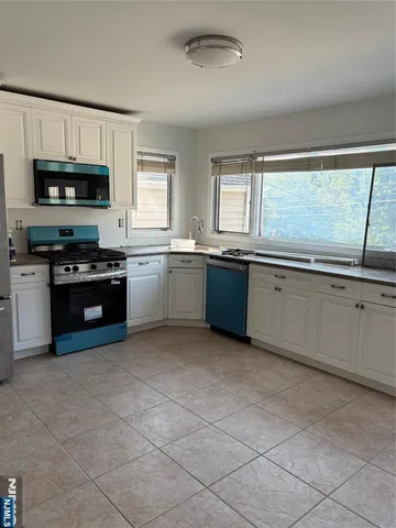 a large kitchen with stainless steel appliances granite countertop a stove granite counter tops and white cabinets