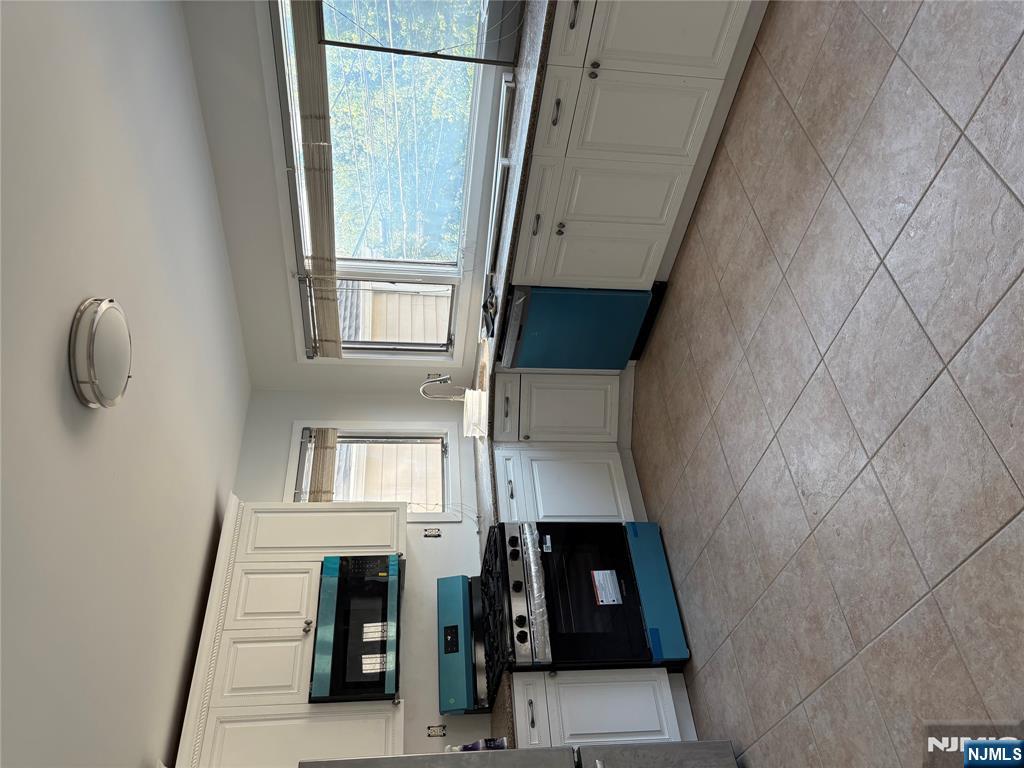 233 Myrtle Avenue, Unit A Fort Lee, NJ 07024 - Photo 3 of 11 a large kitchen with stainless steel appliances granite countertop a stove granite counter tops and white cabinets