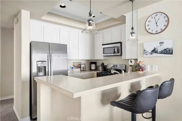 a kitchen with stainless steel appliances granite countertop a refrigerator a sink a stove and a refrigerator with wooden floor