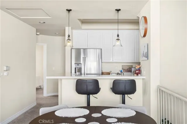 a kitchen with stainless steel appliances kitchen island granite countertop a table chairs and a refrigerator