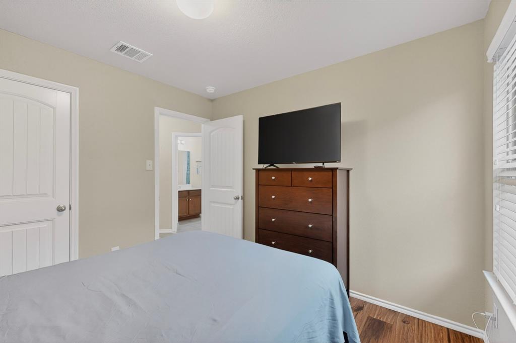 1409 Slate Street Princeton, TX 75407 - Photo 27 of 36 Bedroom featuring wood-finish flooring, neutral wall paint, white trim, and a white interior door