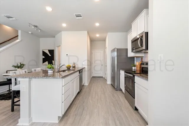 a large kitchen with stainless steel appliances a sink and a refrigerator
