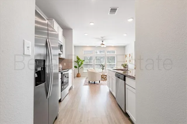 a kitchen with stainless steel appliances a refrigerator a stove a sink and a wooden floors