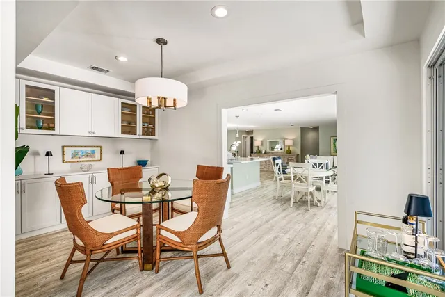a dining room with wooden floor a chandelier a glass table and chairs
