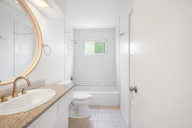 a bathroom with a granite countertop sink a toilet and shower