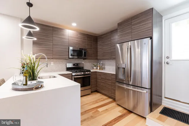 a kitchen with granite countertop a refrigerator a stove a sink a kitchen island with wooden floor and cabinets