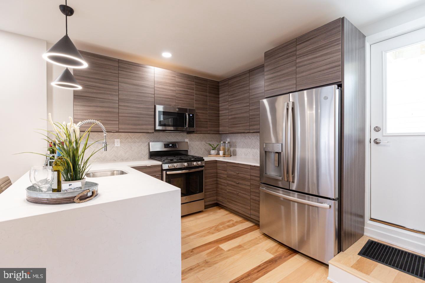 1322 Hope Street, Unit A Philadelphia, PA 19122 - Photo 12 of 30 a kitchen with granite countertop a refrigerator a stove a sink a kitchen island with wooden floor and cabinets