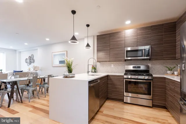 a kitchen with stainless steel appliances a stove a sink a oven a dining table and chairs