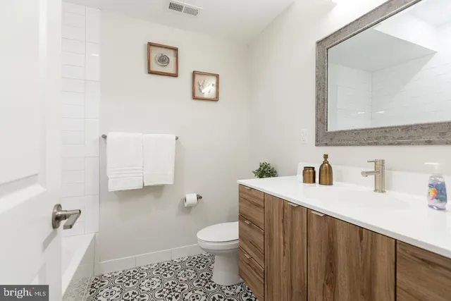 a bathroom with a granite countertop toilet a sink and a mirror