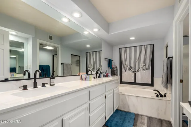 a bathroom with a double vanity sink a mirror and a bathtub