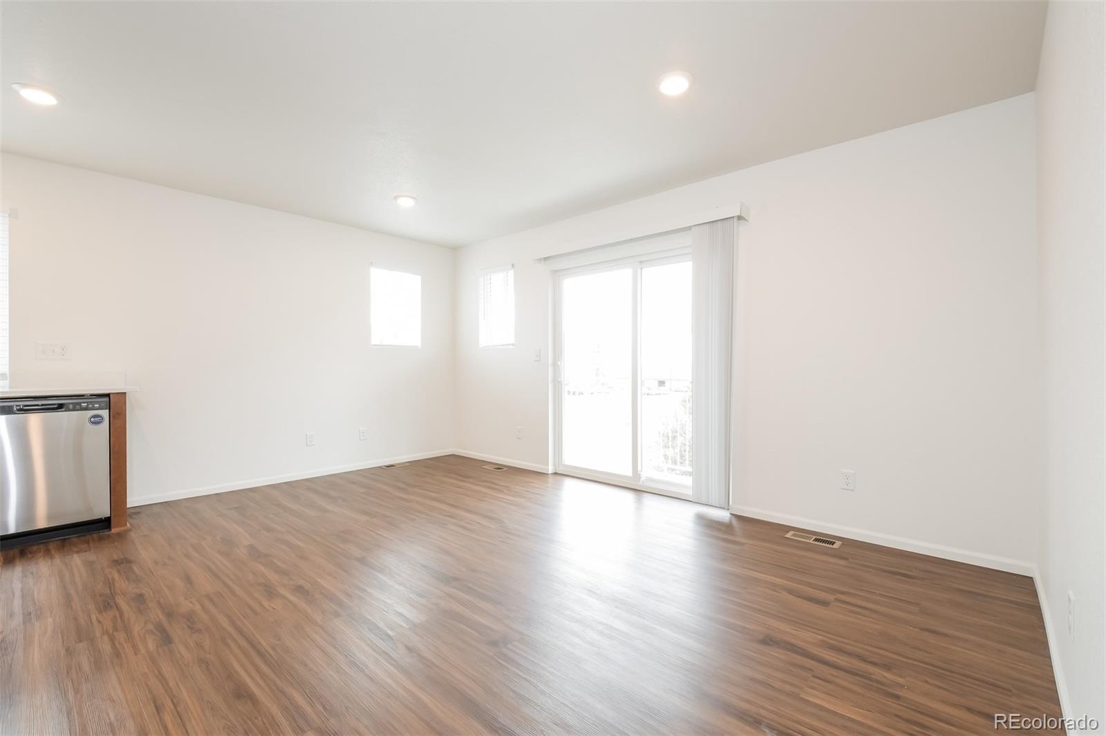 5383 Andes Street Denver, CO 80249 - Photo 2 of 18 a view of an empty room with wooden floor and a window