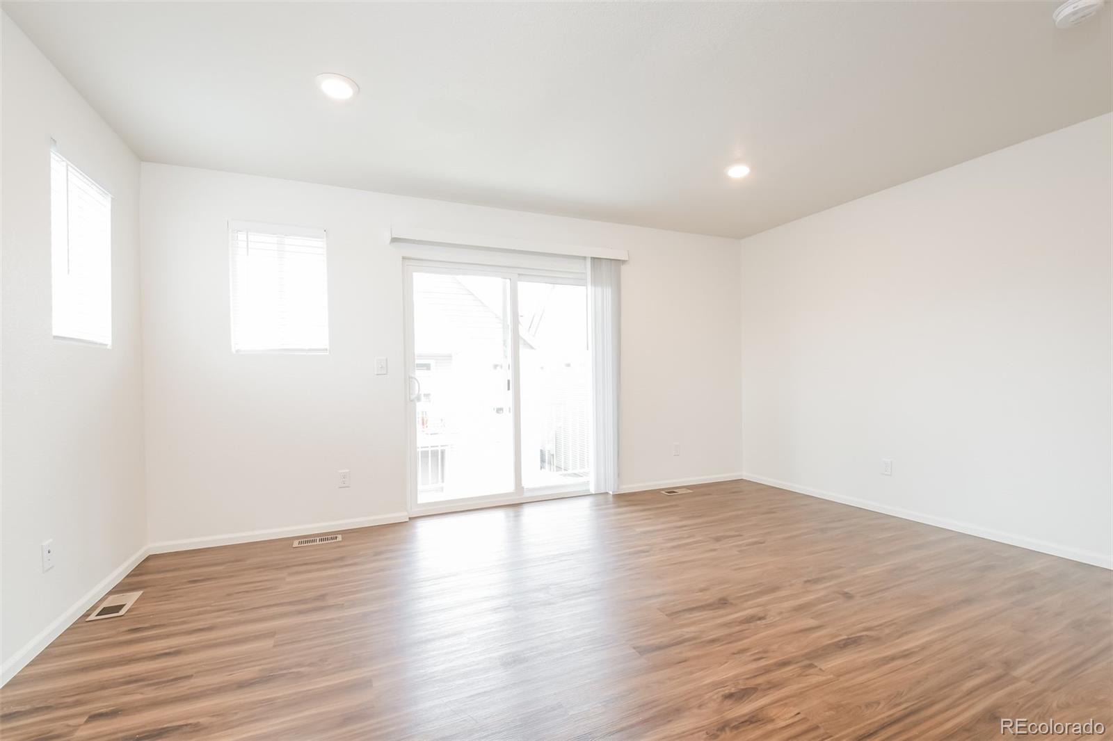 5383 Andes Street Denver, CO 80249 - Photo 3 of 18 a view of an empty room with wooden floor and a window