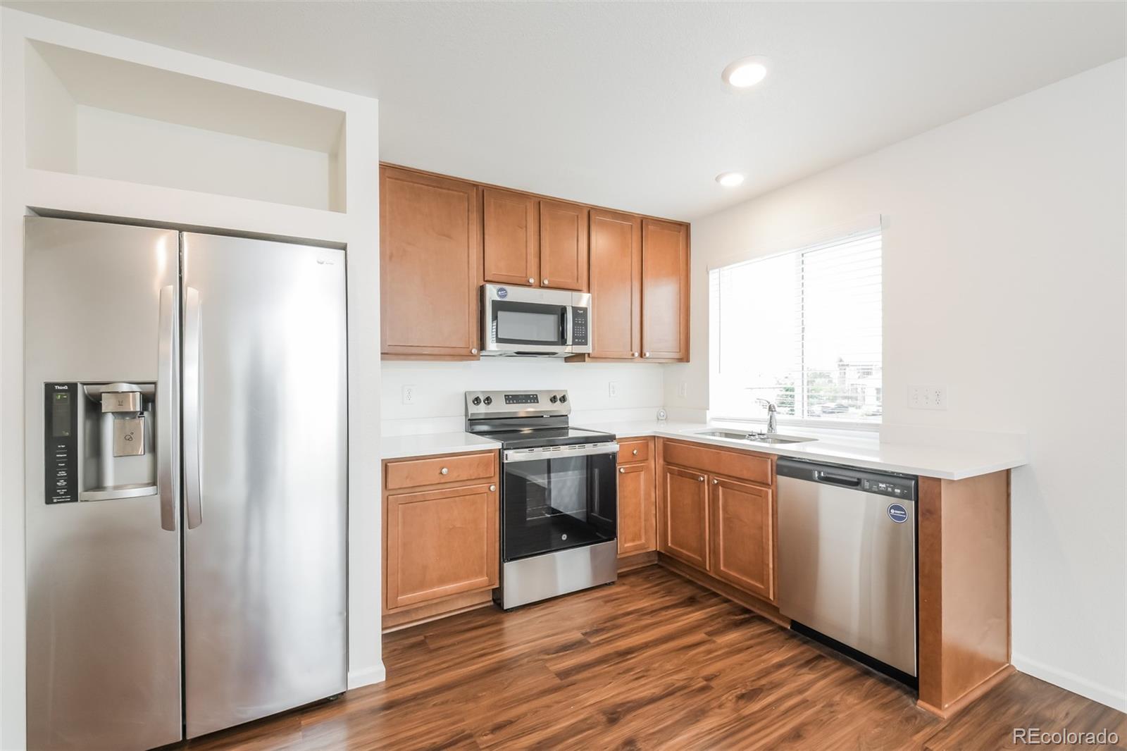 5383 Andes Street Denver, CO 80249 - Photo 6 of 18 a kitchen with stainless steel appliances granite countertop a refrigerator a stove top oven a sink and dishwasher with wooden floor