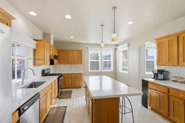 a kitchen with stainless steel appliances granite countertop a sink a stove and a wooden floors