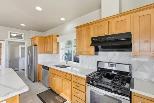 a kitchen with stainless steel appliances granite countertop a stove a sink and a refrigerator