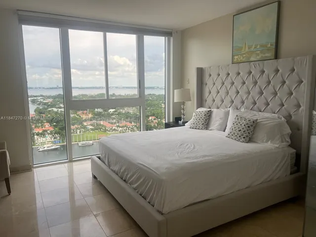 a large bed sitting in a bedroom next to a large window