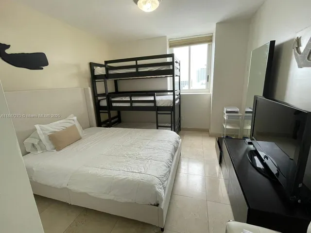 a bedroom with a bed and a flat tv screen on the dresser