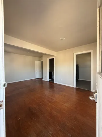 a view of an empty room with wooden floor and closet