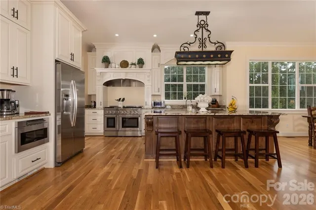 a open kitchen with granite countertop a stove a sink a dining table and chairs with wooden floor