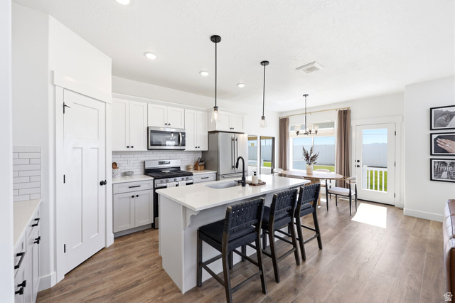 4646 Alder Drive, Unit 223 Mapleton, UT 84664 - Photo 9 of 35 Open-concept kitchen featuring white shaker cabinetry, stainless steel appliances, a subway tile backsplash, and a large island with a countertop