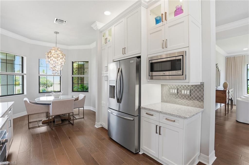 4220 Amelia Way Naples, FL 34119 - Photo 13 of 50 a kitchen with stainless steel appliances a refrigerator a stove top oven a sink dishwasher and white cabinets with wooden floor