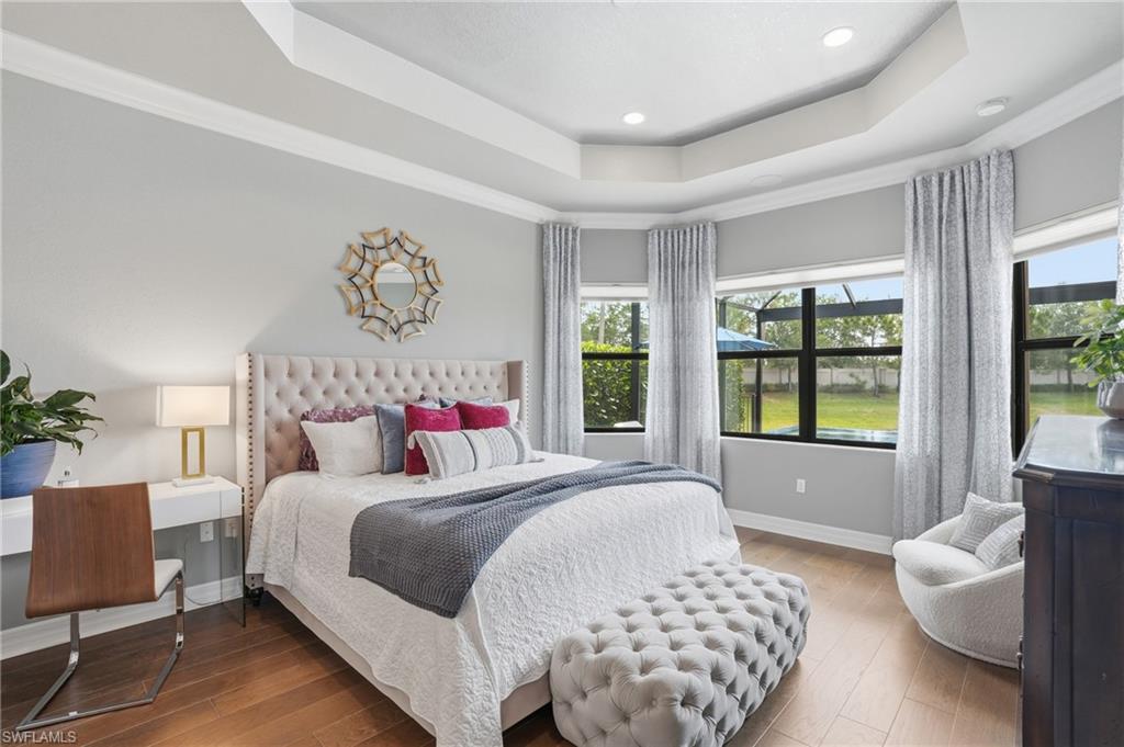 4220 Amelia Way Naples, FL 34119 - Photo 17 of 50 a bedroom with a bed and wooden floor