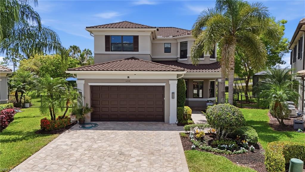 4220 Amelia Way Naples, FL 34119 - Photo 2 of 50 a front view of a house with a garden and trees