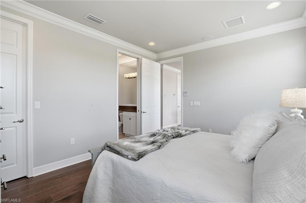 4220 Amelia Way Naples, FL 34119 - Photo 26 of 50 a bedroom with a bed and wooden floor
