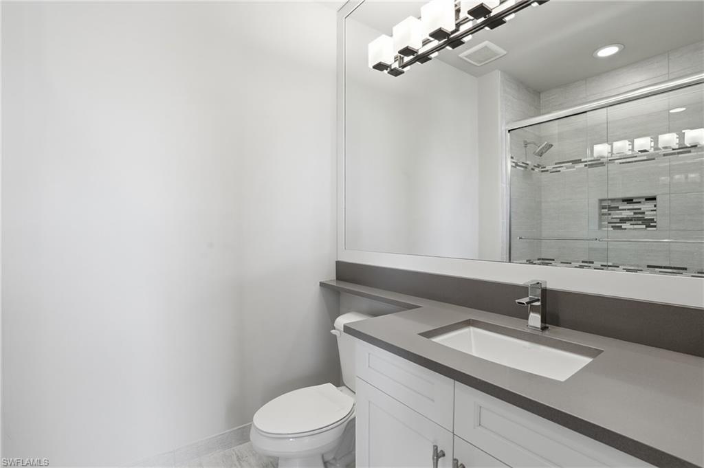 4220 Amelia Way Naples, FL 34119 - Photo 27 of 50 a bathroom with a sink vanity granite toilet and a mirror