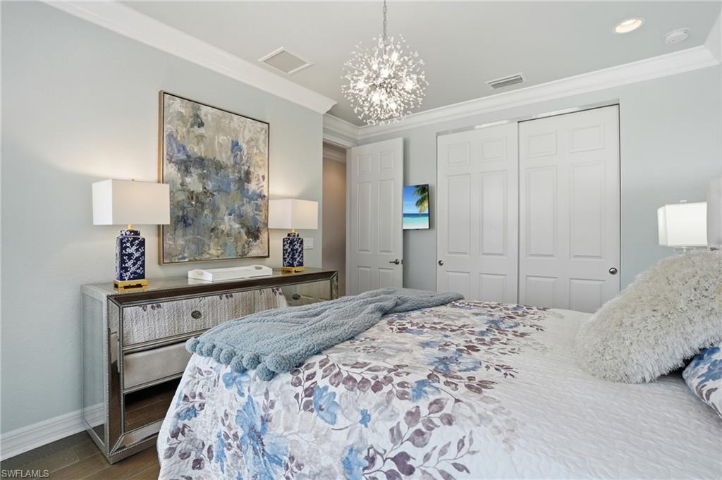 4220 Amelia Way Naples, FL 34119 - Photo 29 of 50 a bedroom with a large bed and a chandelier