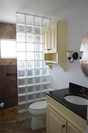 a bathroom with a granite countertop sink a toilet and a shower